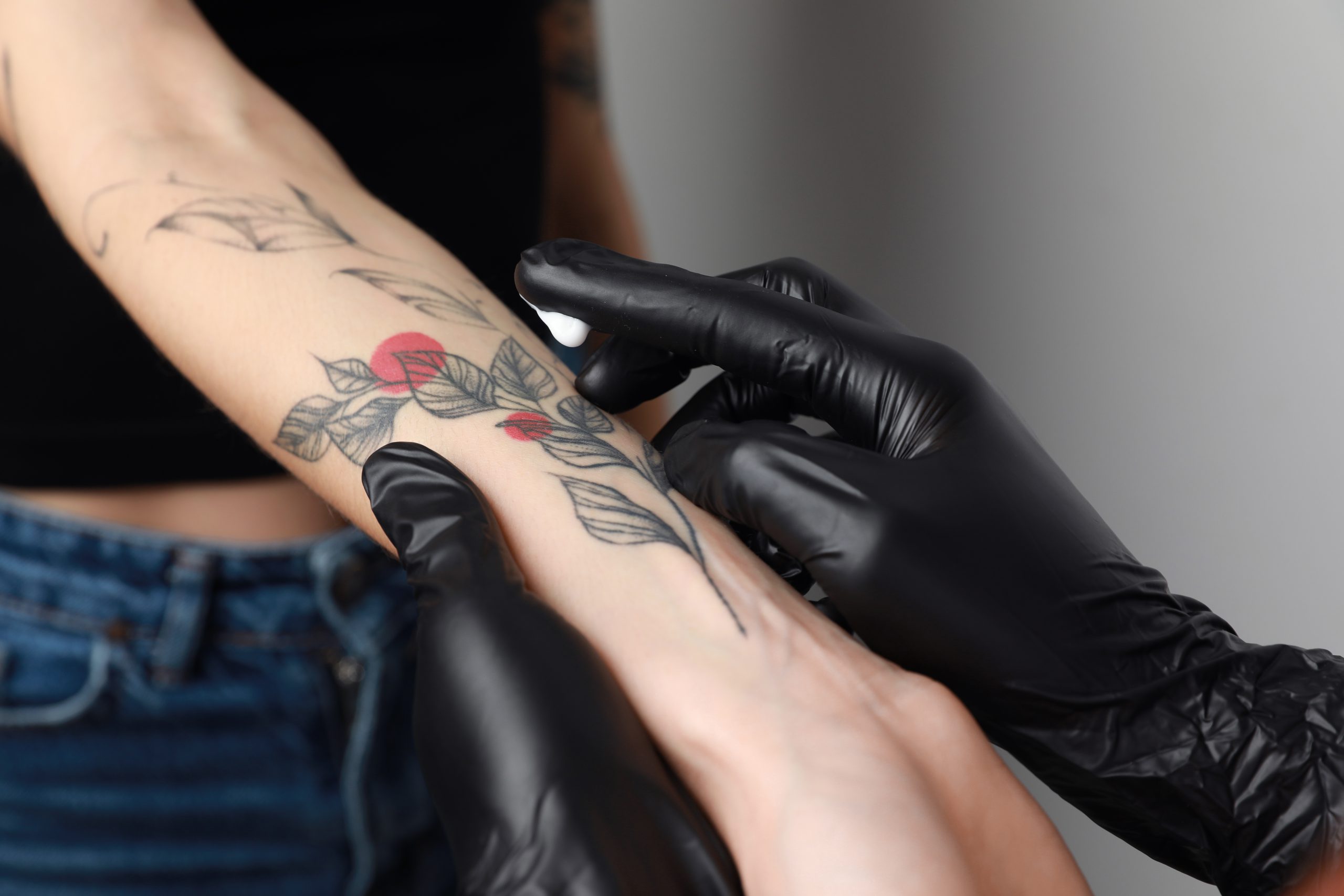 Worker,In,Gloves,Applying,Cream,On,Woman’s,Arm,With,Tattoo